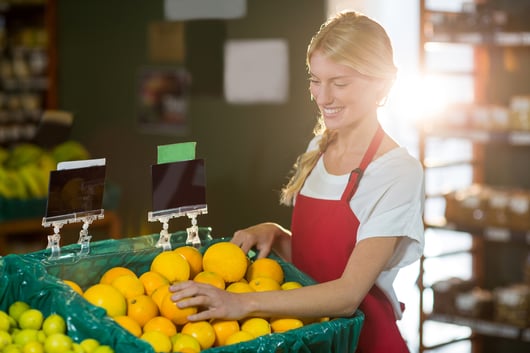 Smiling female staff checking fruits in organic section of supermarket